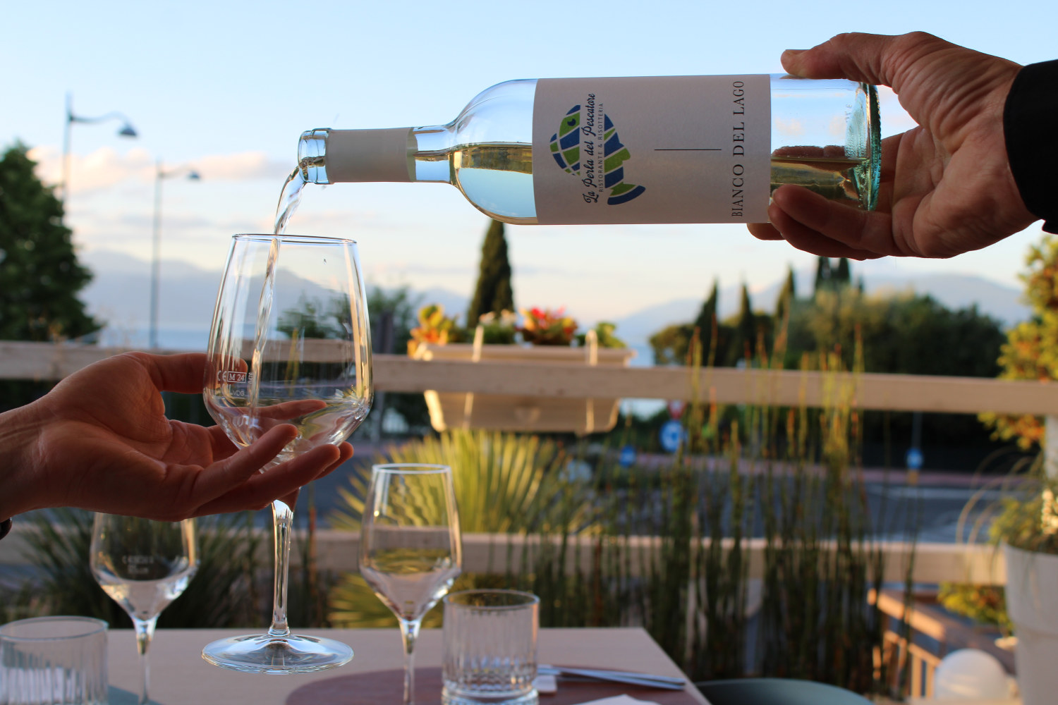 Servizio del vino sulla terrazza del ristorante di pesce vista lago La Perla del Pescatore a Desenzano.