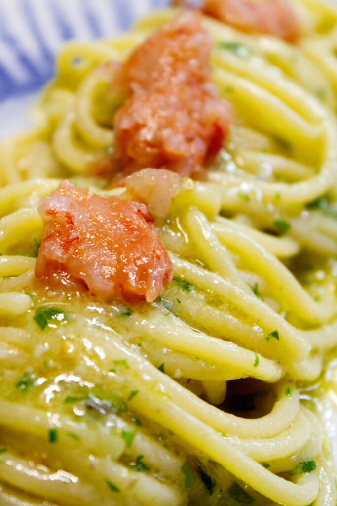 Dettaglio macro di un primo piatto di spaghetti mantecati con tartare di gamberi rossi crudi freschissimi, specialità d'autore del ristorante La Perla del Pescatore a Desenzano del Garda.
